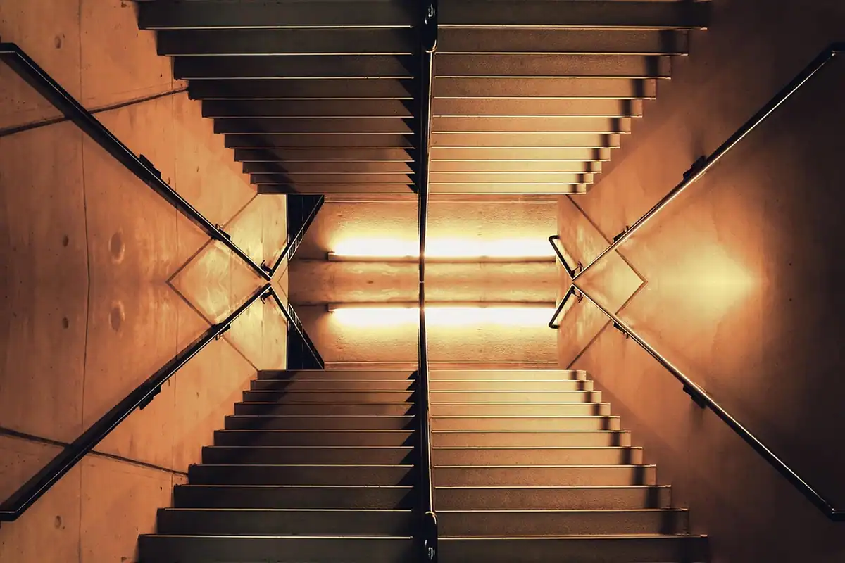 Scară simetrică luminată cald, văzută de jos, exemplu de compoziție cu linii și simetrie