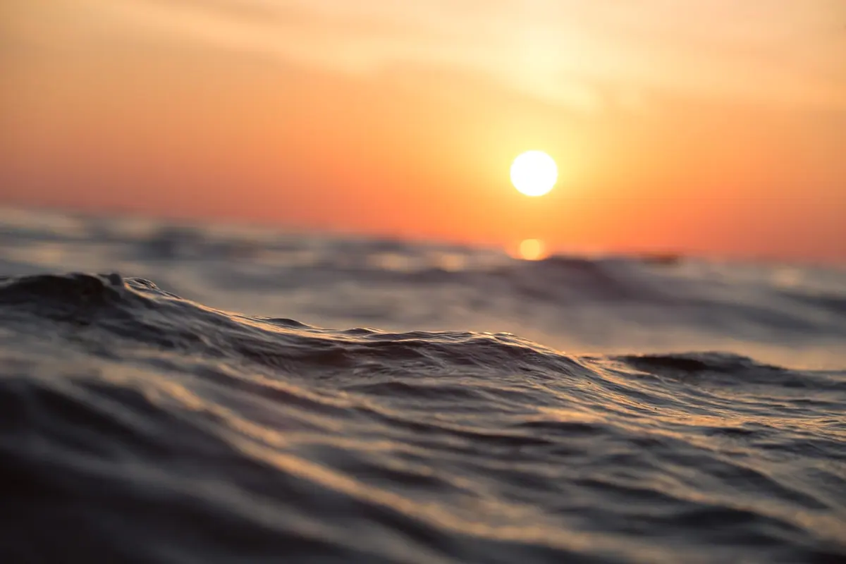 Soare la orizont peste valuri de mare, linia apei servind drept reper pentru îndreptare