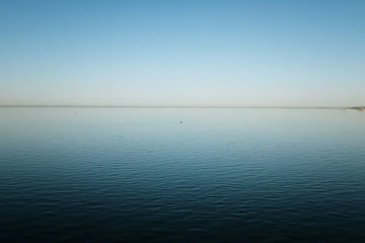 Linie dreaptă a orizontului peste o mare calmă la amurg, cu cer limpede deasupra