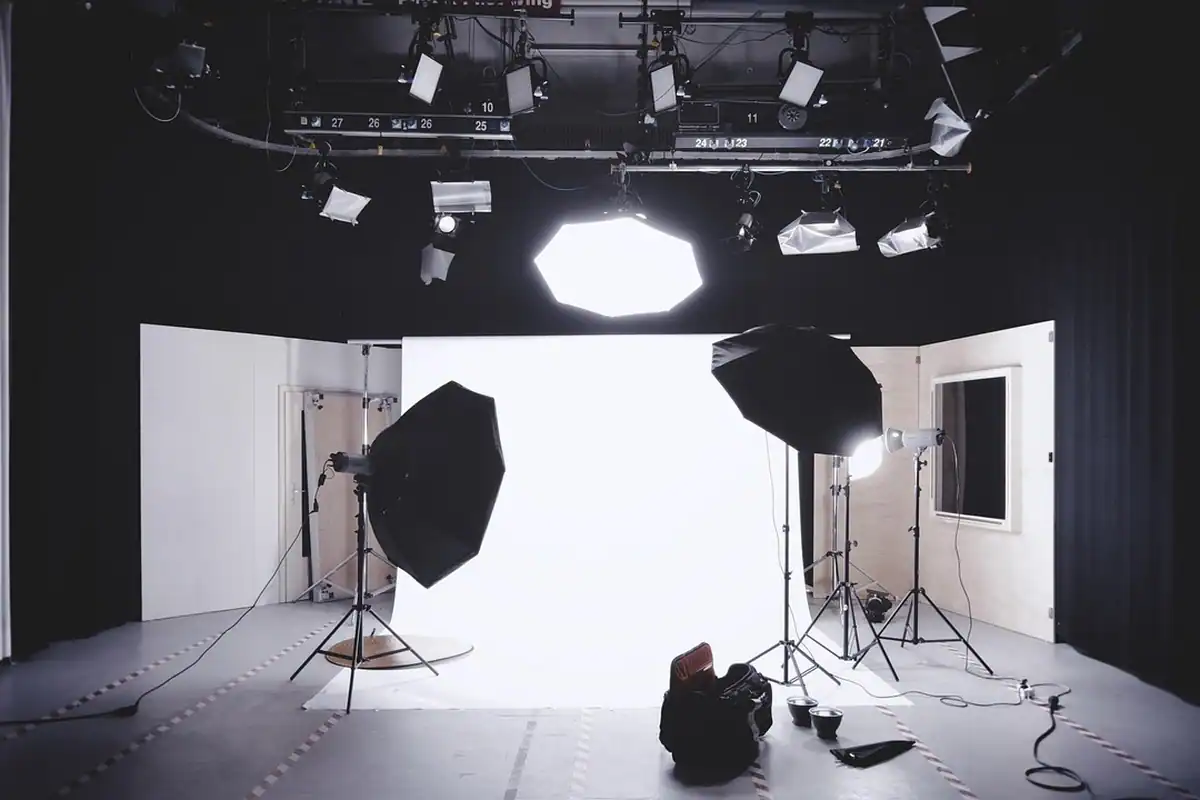 Studio cu softboxuri, lumini pe stative și fundal alb pentru iluminat în trei puncte