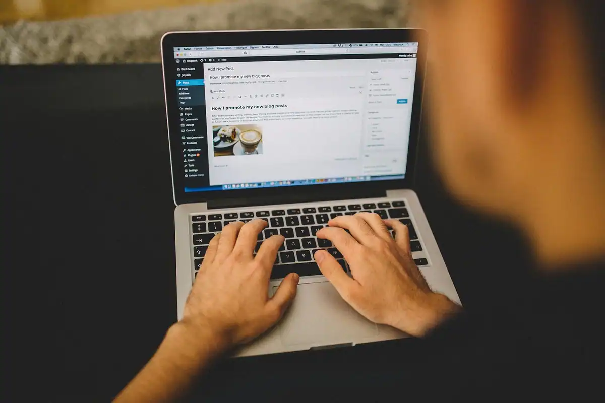 Mâini care tastează pe un laptop, lângă o ceașcă, în timpul unei sesiuni de montaj