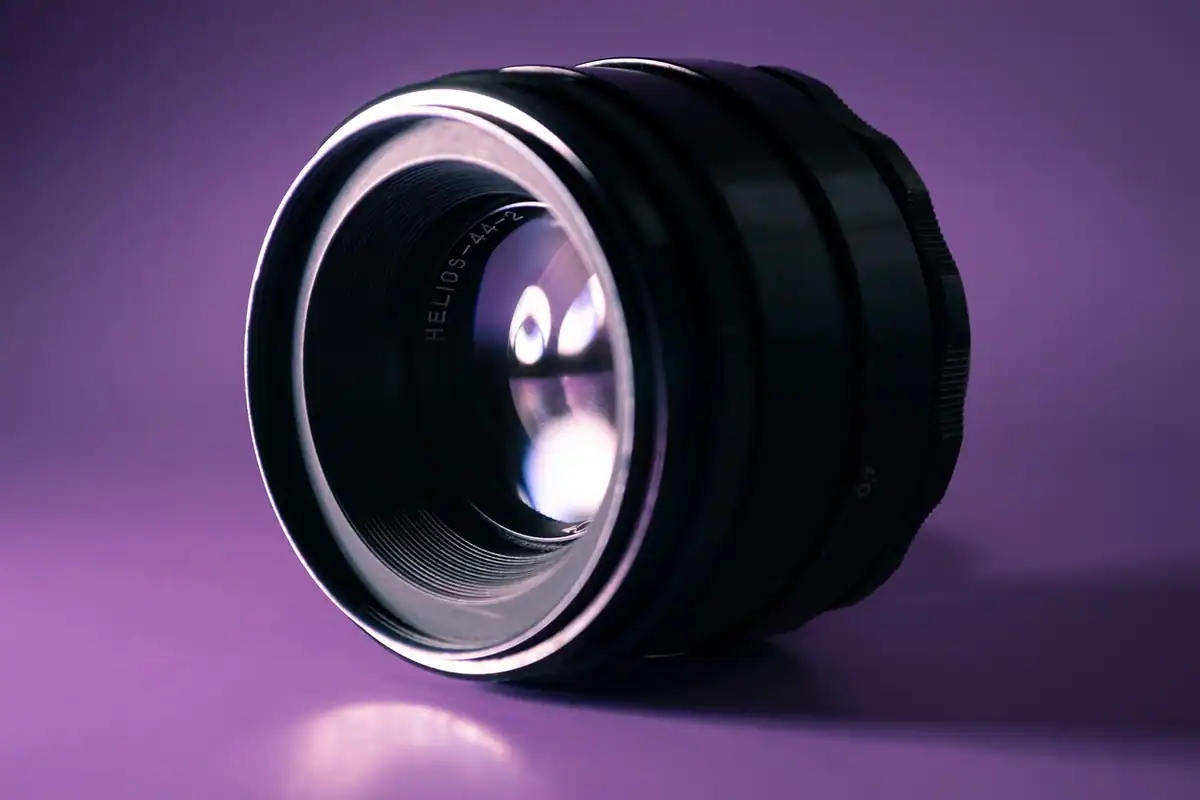 Obiectiv fix negru cu reflexii violet pe sticla frontală, privit din lateral