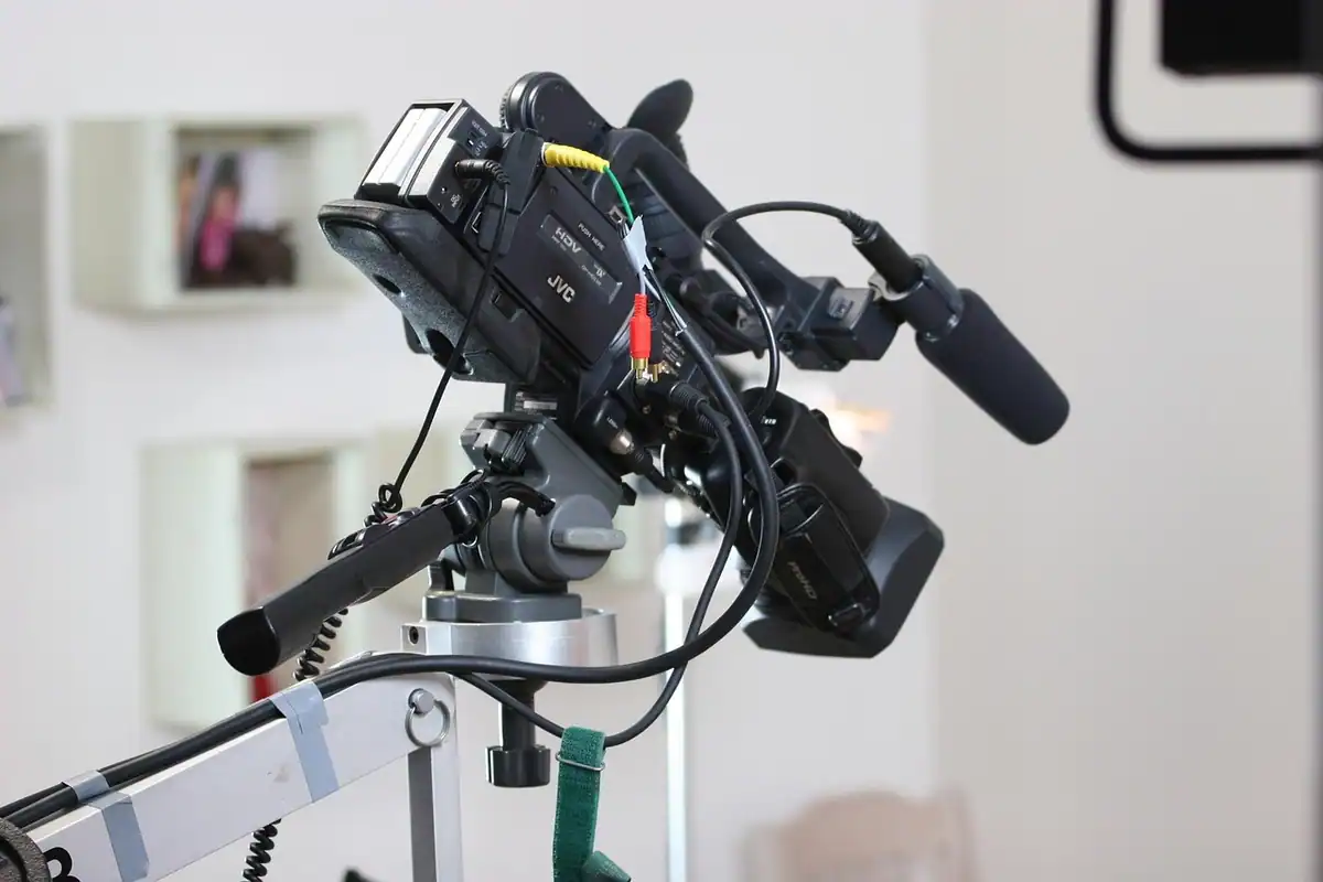 Cameră video cu microfon pe un trepied cu cap fluid, într-o încăpere luminoasă