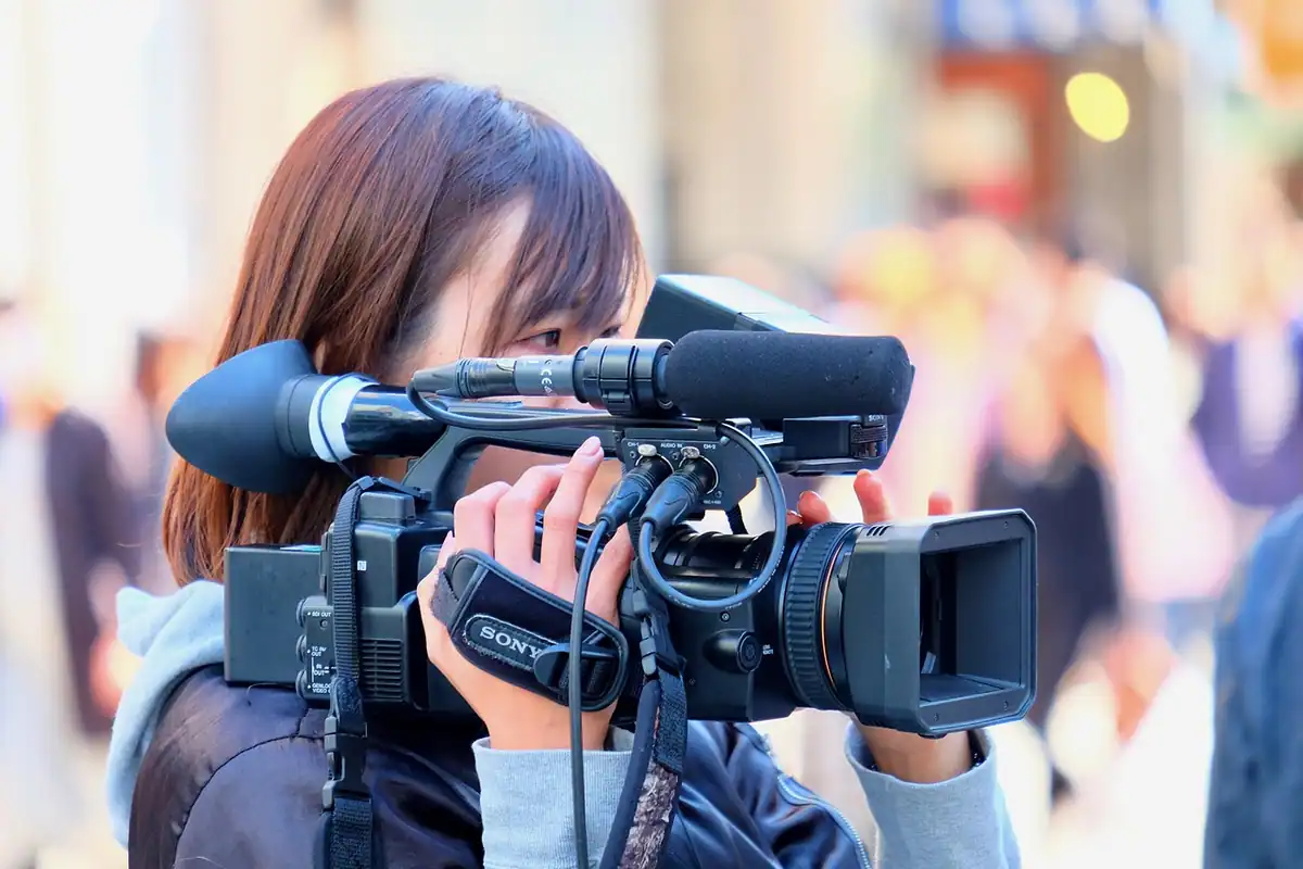 Femeie care filmează pe stradă cu o cameră video cu microfon montat deasupra