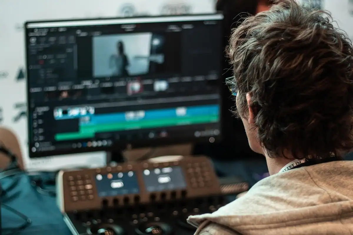 Montor la un birou cu ecrane cu program de editare video, văzut din spate